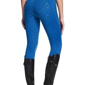 Dame im Reitsport-Outfit mit blauen Strumpfhosen von Baleaf und schwarzen Stiefeln auf weißem Hintergrund